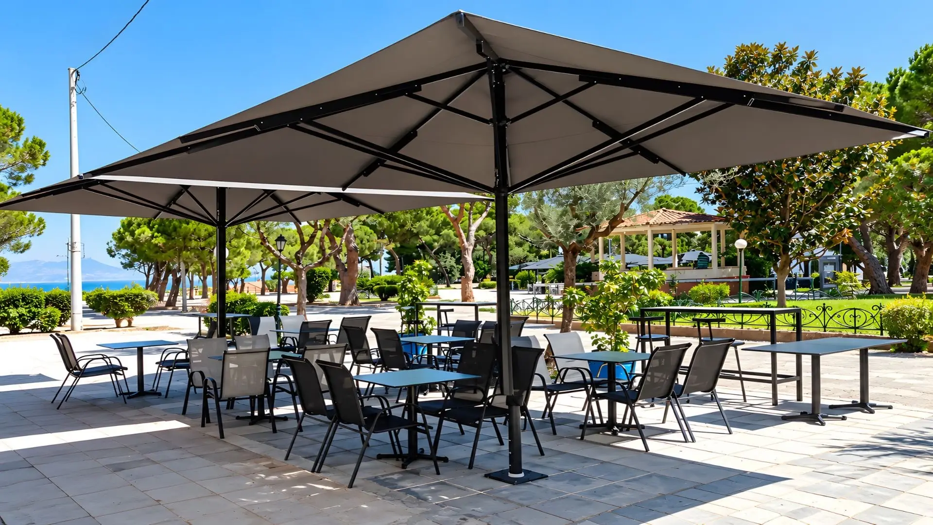 Outdoor seating at Zygos in Ypsila Alonia, Aigio, with umbrellas and a view of the park and the sea